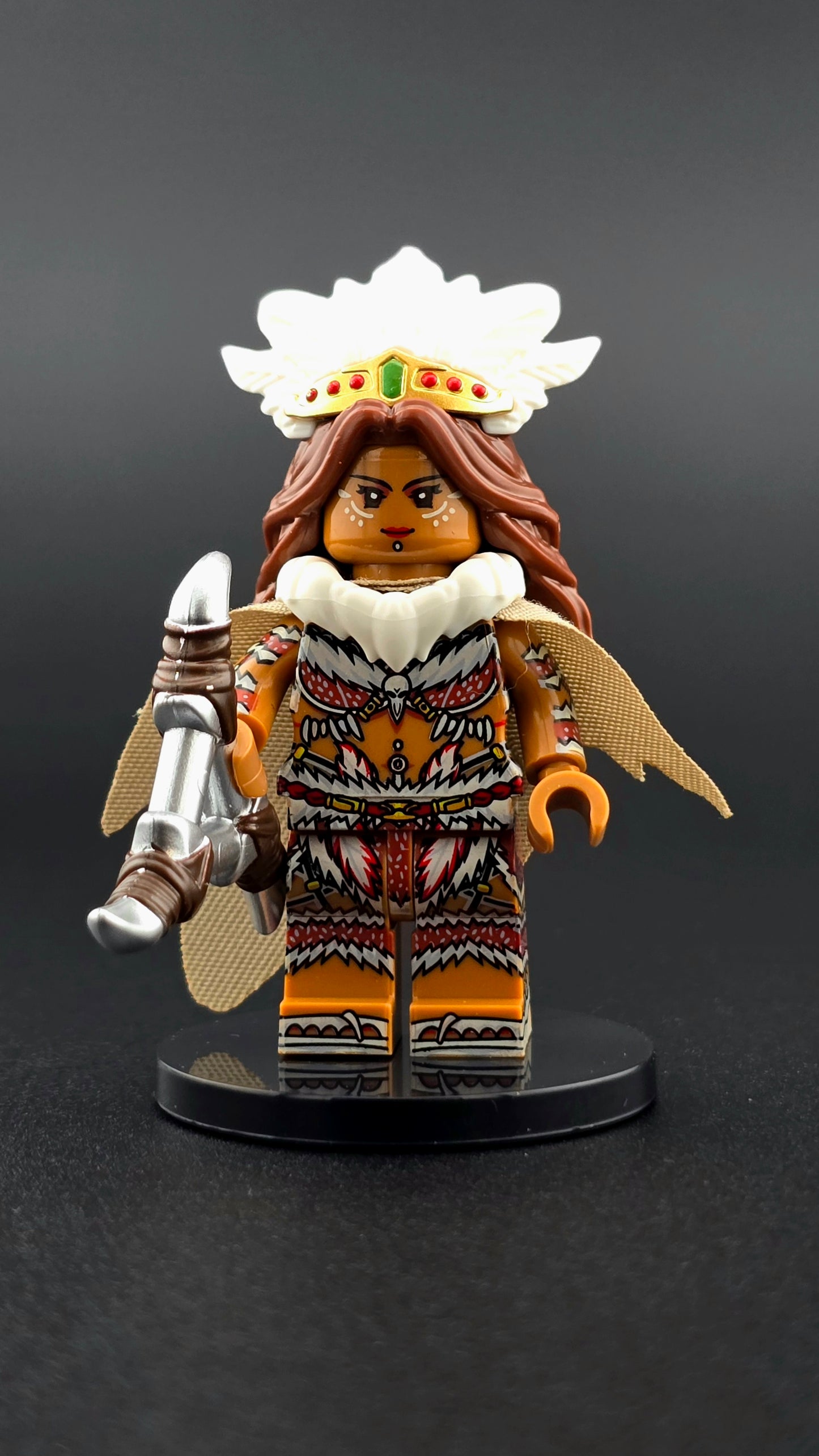 Custom fantasy inspired Jungle Matriarch minifigure with intricate headdress, brown and white armor, golden accents, fur details, cape, and throwing weapon. Detailed tribal priestess design compatible with leading brick style building sets.
