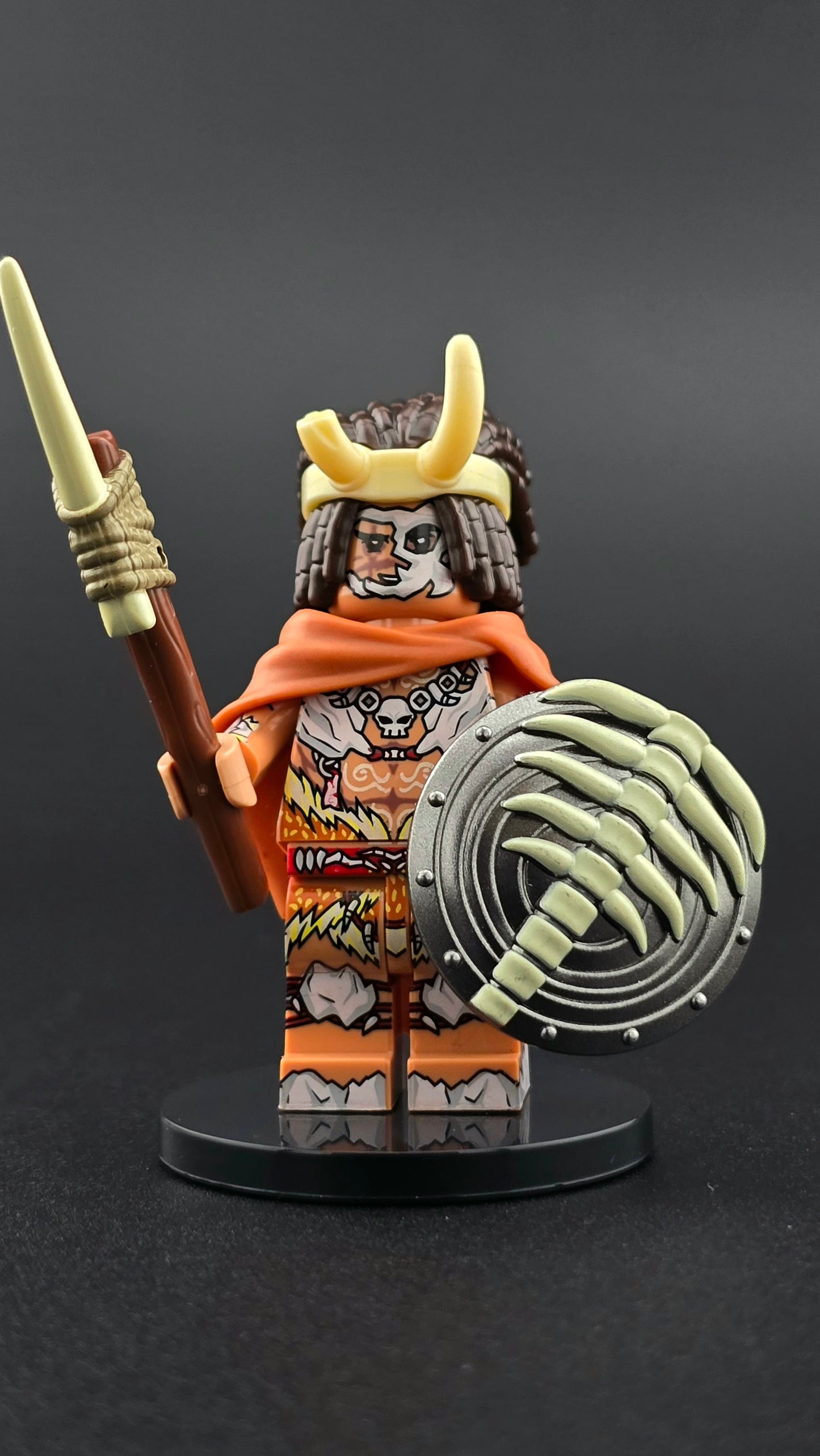 Custom fantasy inspired Deathmask Warrior minifigure with skull face paint, horned headgear, brown and white fur armor, orange accents, bone spear, and spine shield. Designed with detailed tribal warrior styling compatible with leading brick style building sets.