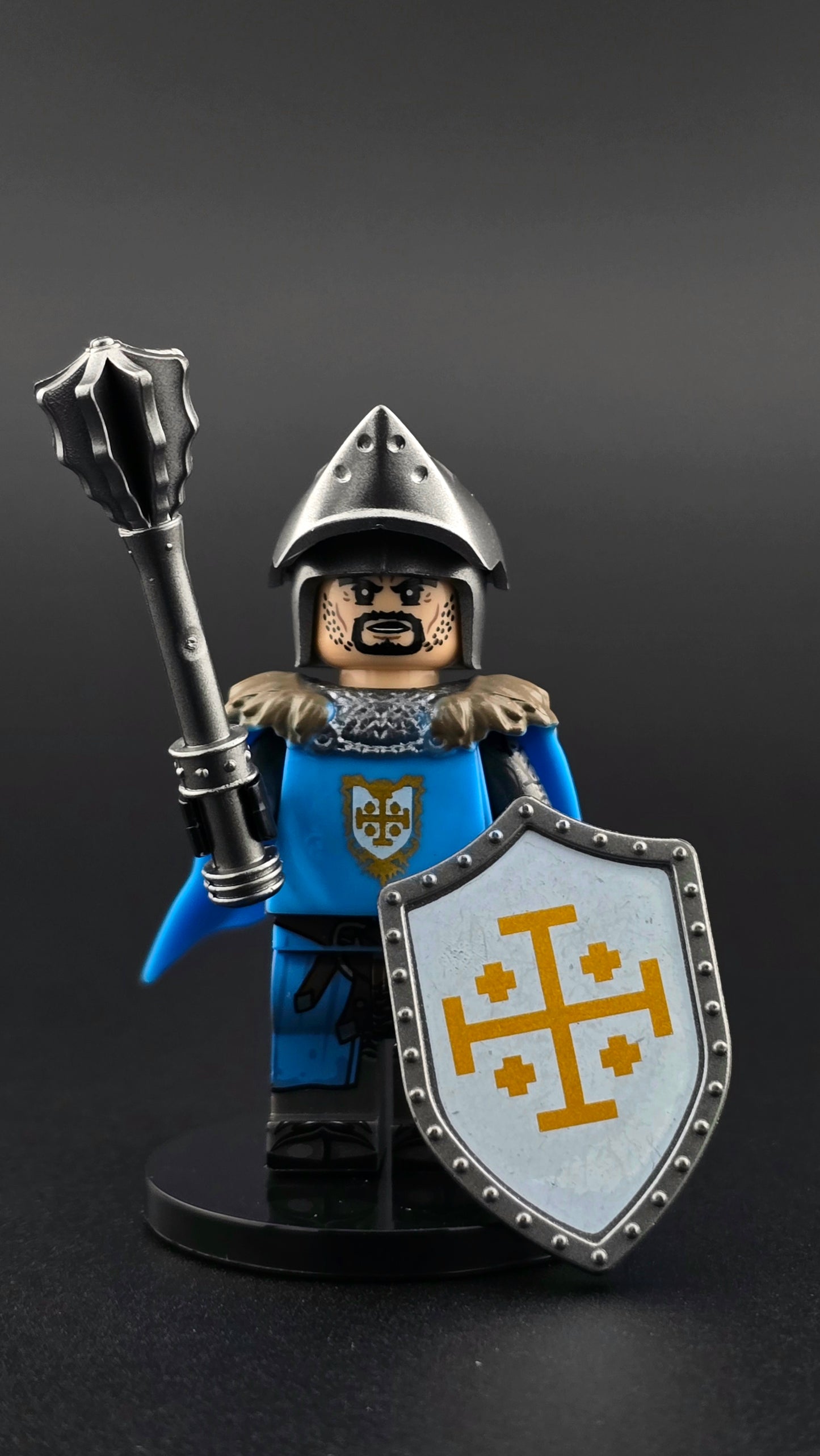 Custom medieval Jerusalem Knight minifigure in blue, white, and silver armor with open bacinet helm, detailed cross emblem, and flowing cape, posed with mace and shield accessories and compatible with leading brick-style systems.