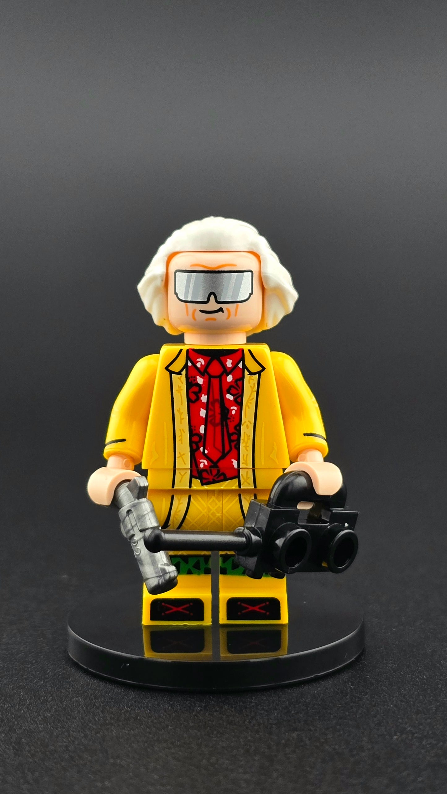 Custom movie-inspired Doc Brown minifigure in bright yellow suit with wild scientist details, equipped with pistol and tech gadget accessories, compatible with leading brick-style building systems.