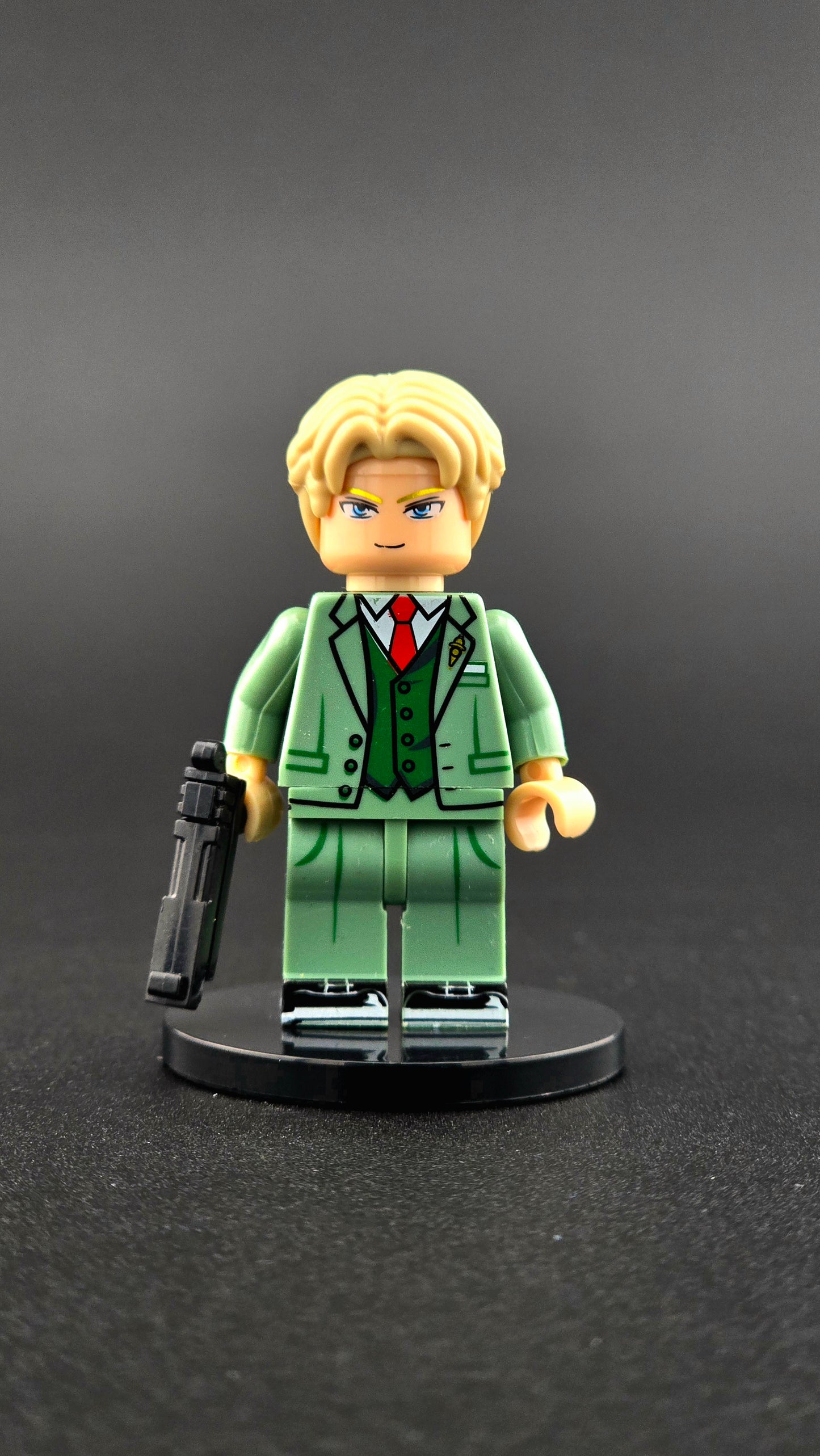 Custom anime-inspired Loid Forger minifigure wearing a green suit with a handgun accessory and dual-sided head, based on Spy X Family and compatible with leading brick-style building systems.