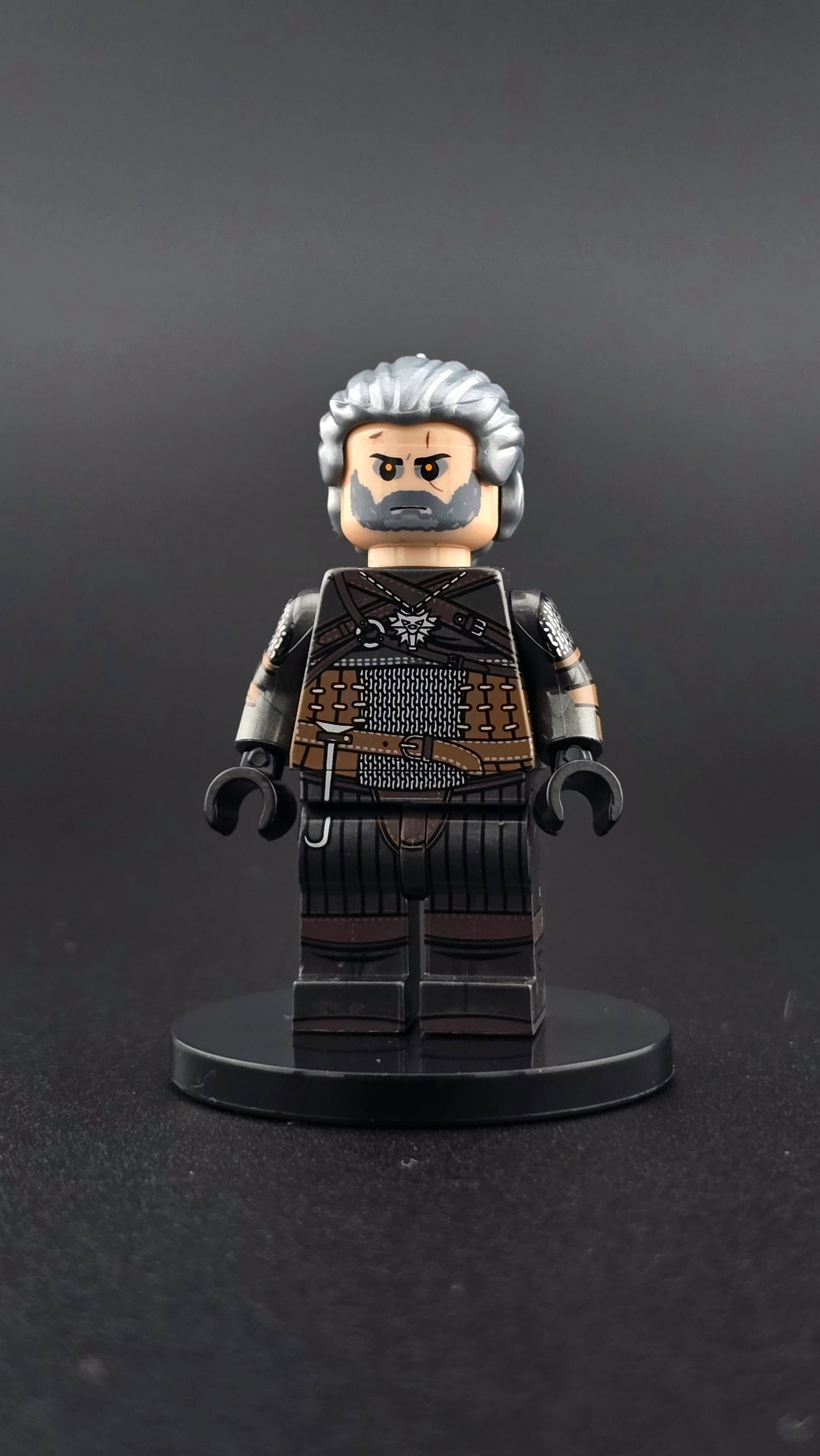 Custom gaming inspired Geralt minifigure with black, grey, and brown outfit, glowing eyes, and dual swords. Detailed monster hunter design compatible with leading brick style building sets.