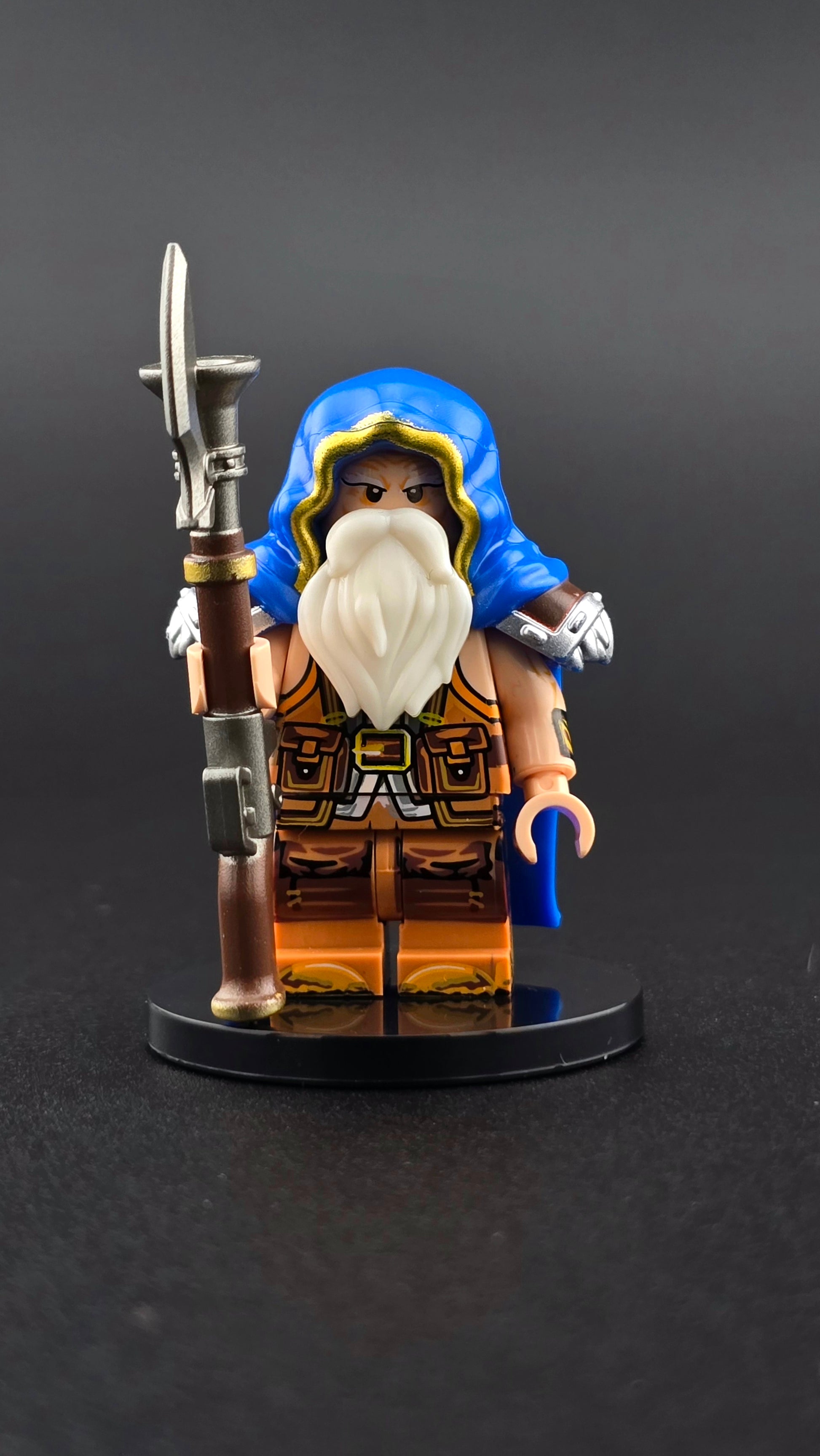 Custom fantasy inspired Dwarf Rifleman minifigure with royal blue hood and cape, orange accents, full beard, and detailed rifle. Designed with steampunk dwarf styling compatible with leading brick style building sets.