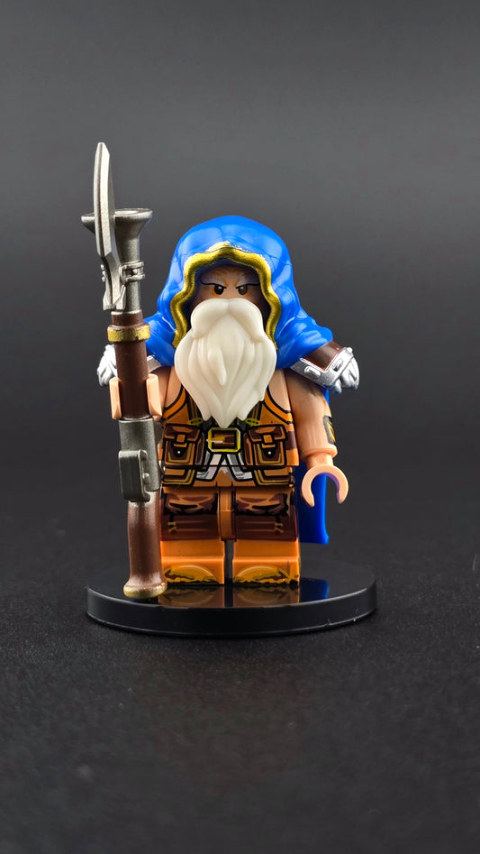 Custom fantasy inspired Dwarf Rifleman minifigure with royal blue hood and cape, orange accents, full beard, and detailed rifle. Designed with steampunk dwarf styling compatible with leading brick style building sets.