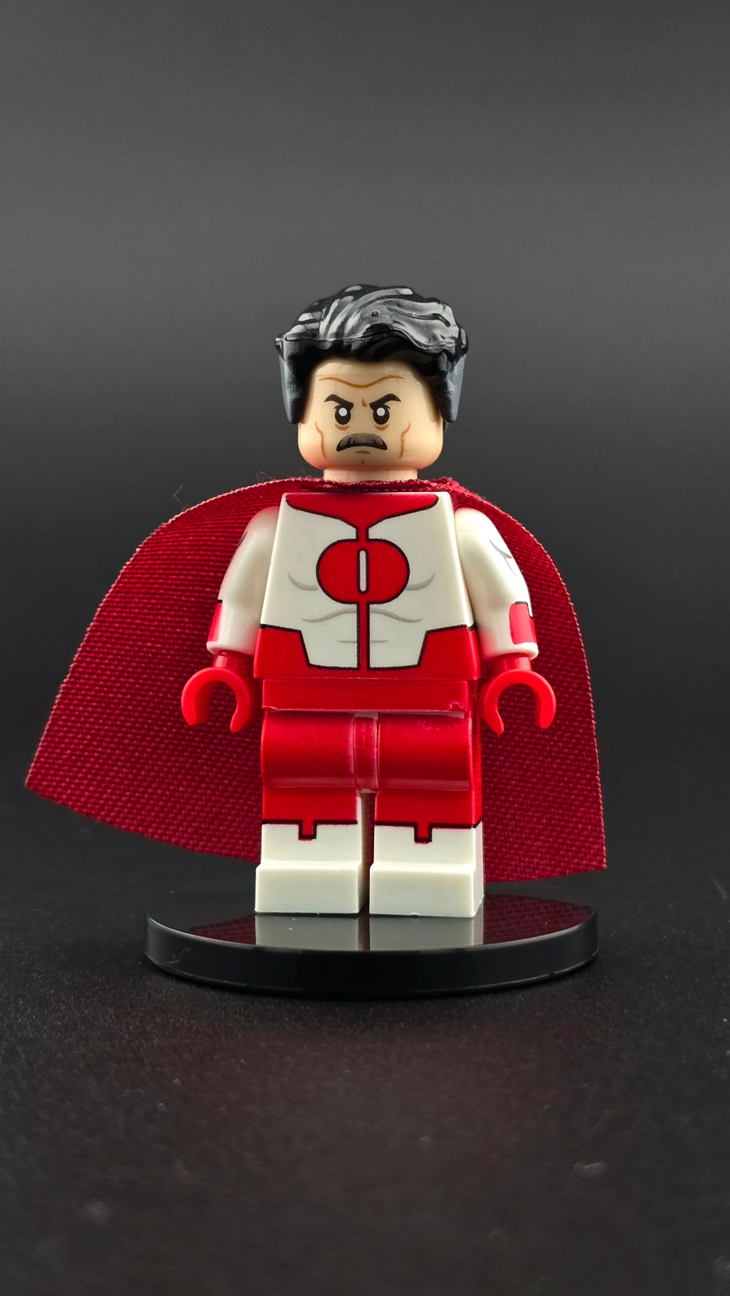 Custom TV inspired superhero villain minifigure in red and white suit with dual sided head, stern expression, mustache, and flowing red cape. Detailed premium design compatible with leading brick style building sets.