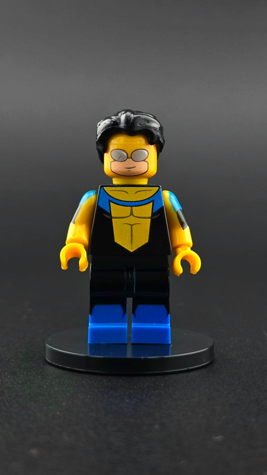 Custom TV inspired superhero minifigure in black, blue, and yellow suit with dual sided head and dynamic facial expressions. Detailed premium design compatible with leading brick style building sets.