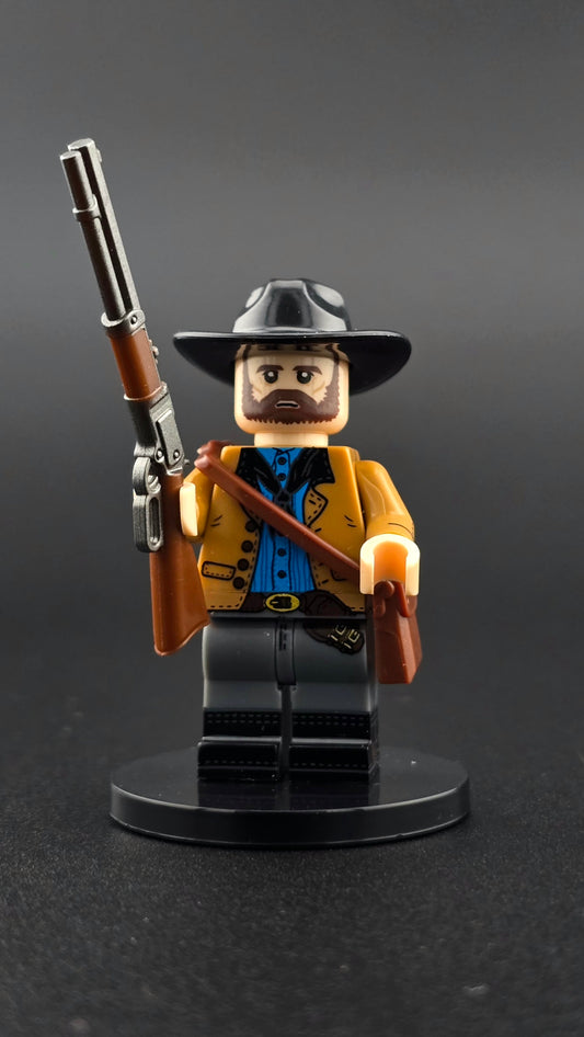 Custom gaming inspired Arthur Morgan minifigure with black, tan, blue, and brown cowboy attire, satchel accessory, and rifle. Detailed Wild West gunslinger design compatible with leading brick style building sets.