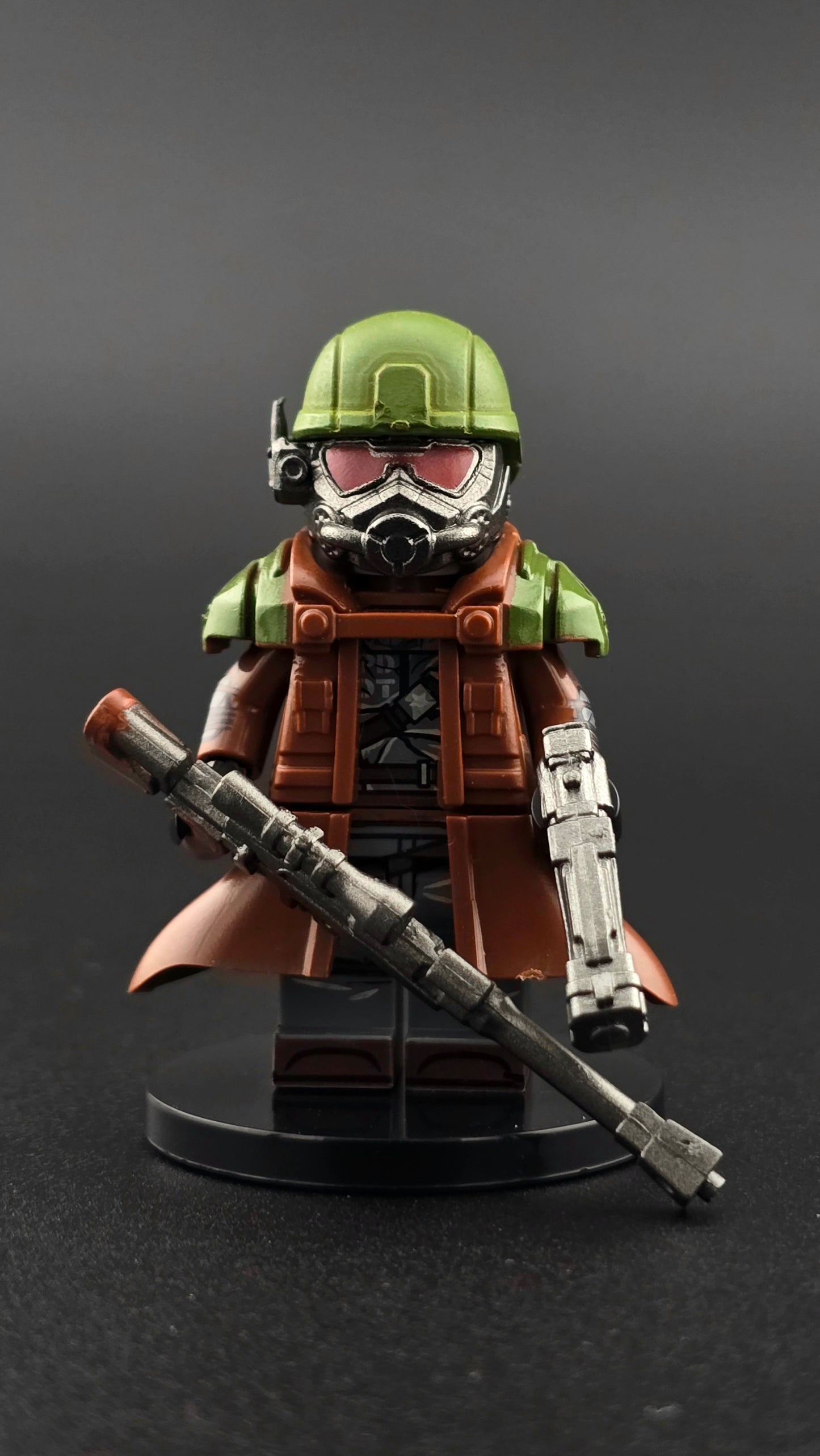 Custom gaming inspired ranger minifigure with brown duster, green and gray armor, masked helmet, sniper rifle, and pistol. Detailed post apocalyptic desert themed design compatible with leading brick style building sets.