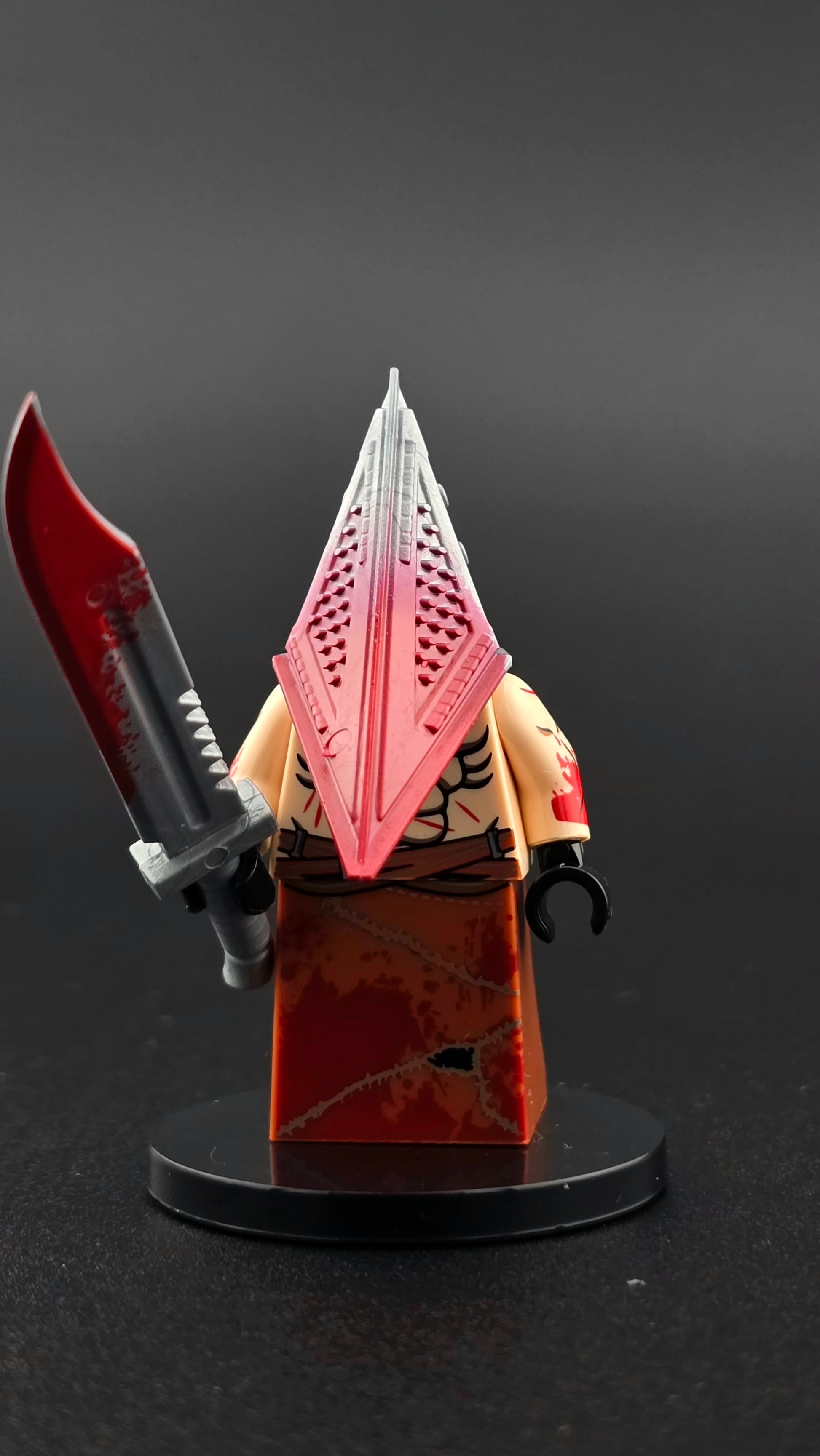 Custom gaming inspired Pyramid Head minifigure in red with iconic helmet, muscular build, and massive large blade accessory. Detailed survival horror design compatible with leading brick style building sets.