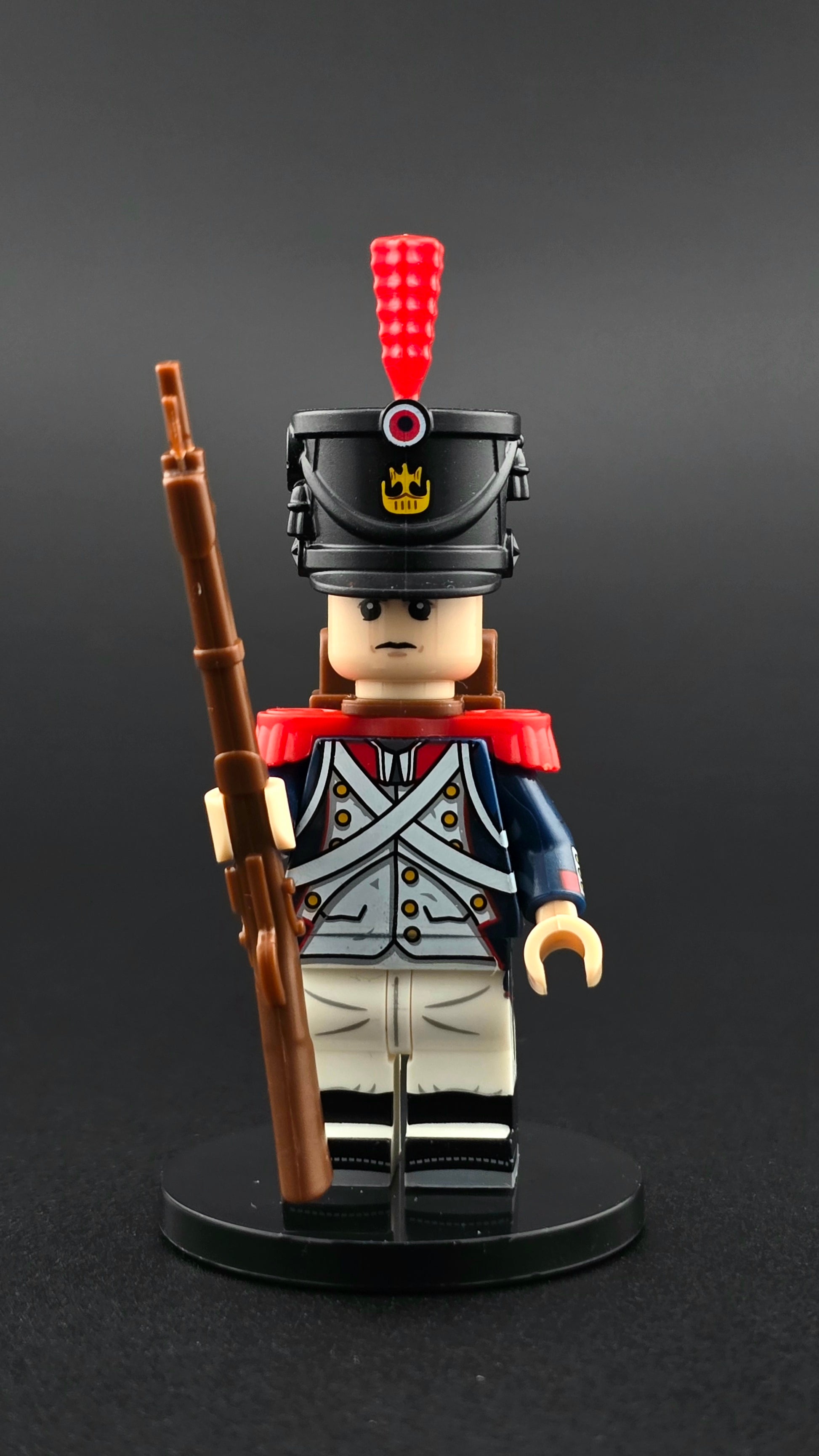 Custom French Napoleonic Soldier minifigure in blue, white, and red uniform with shako and red plume, equipped with rifle and backpack accessories, compatible with leading brick-style building systems.