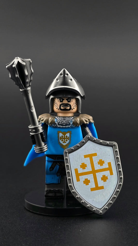 Custom medieval Jerusalem Knight minifigure in blue, white, and silver armor with open bacinet helm, detailed cross emblem, and flowing cape, posed with mace and shield accessories and compatible with leading brick-style systems.