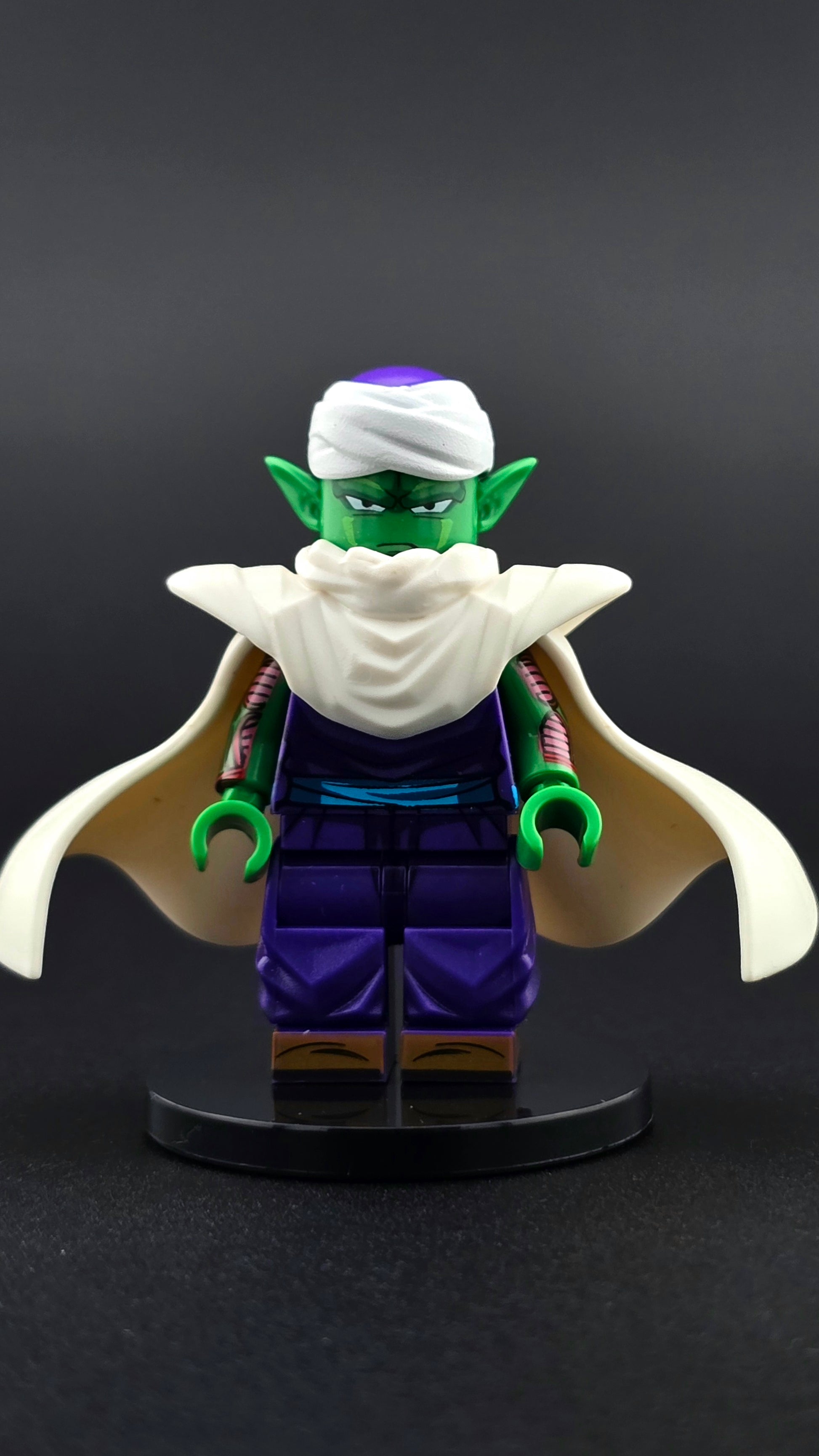 Custom anime inspired Piccolo minifigure with green skin, white cape, turban, and energy force accessory. Detailed Namekian fighter design compatible with leading brick style building sets.