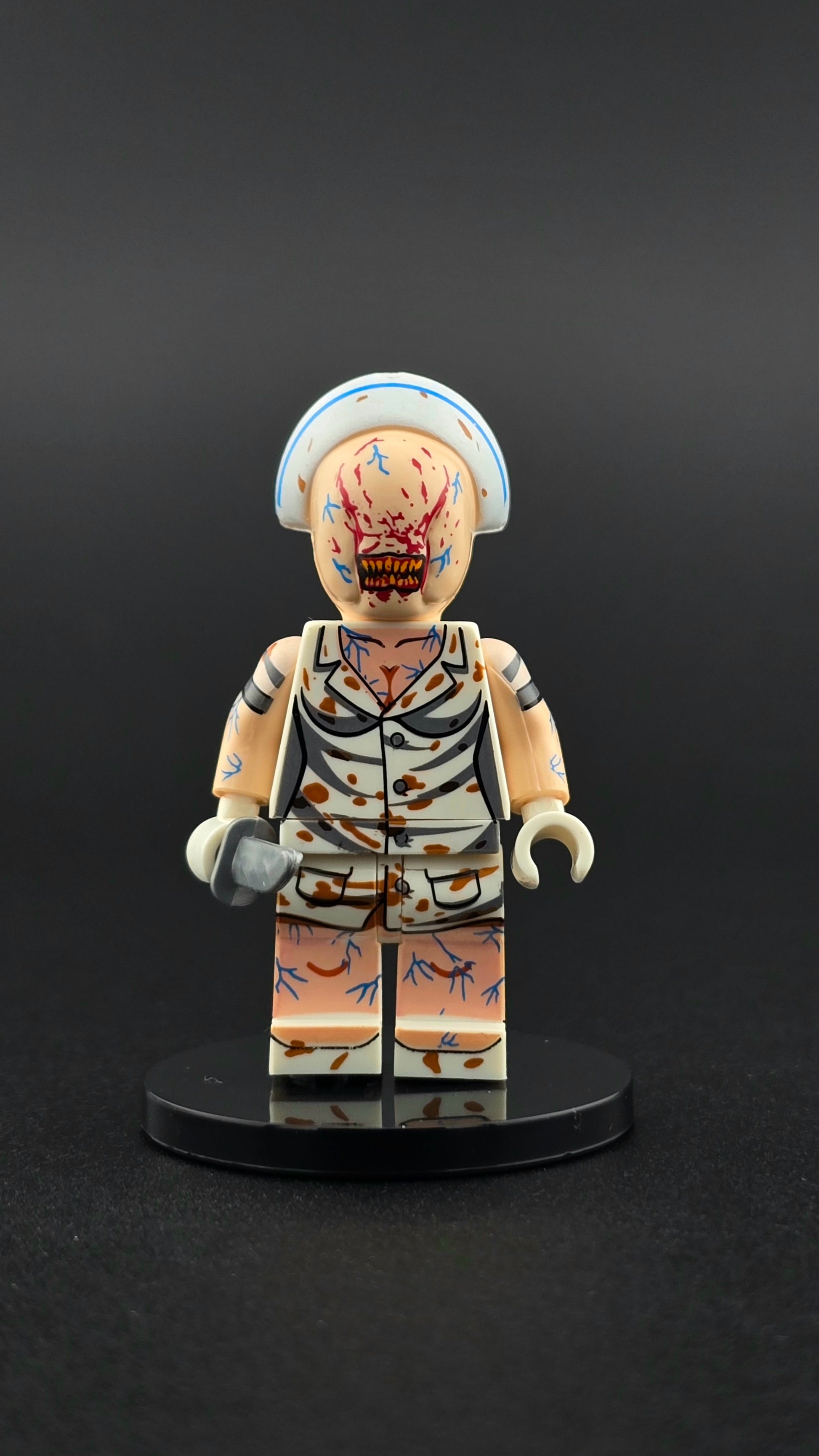 Custom gaming inspired Silent Hill nurse minifigure in white with vein details, eerie expression, and knife accessory. Designed with unsettling horror styling compatible with leading brick style building sets.
