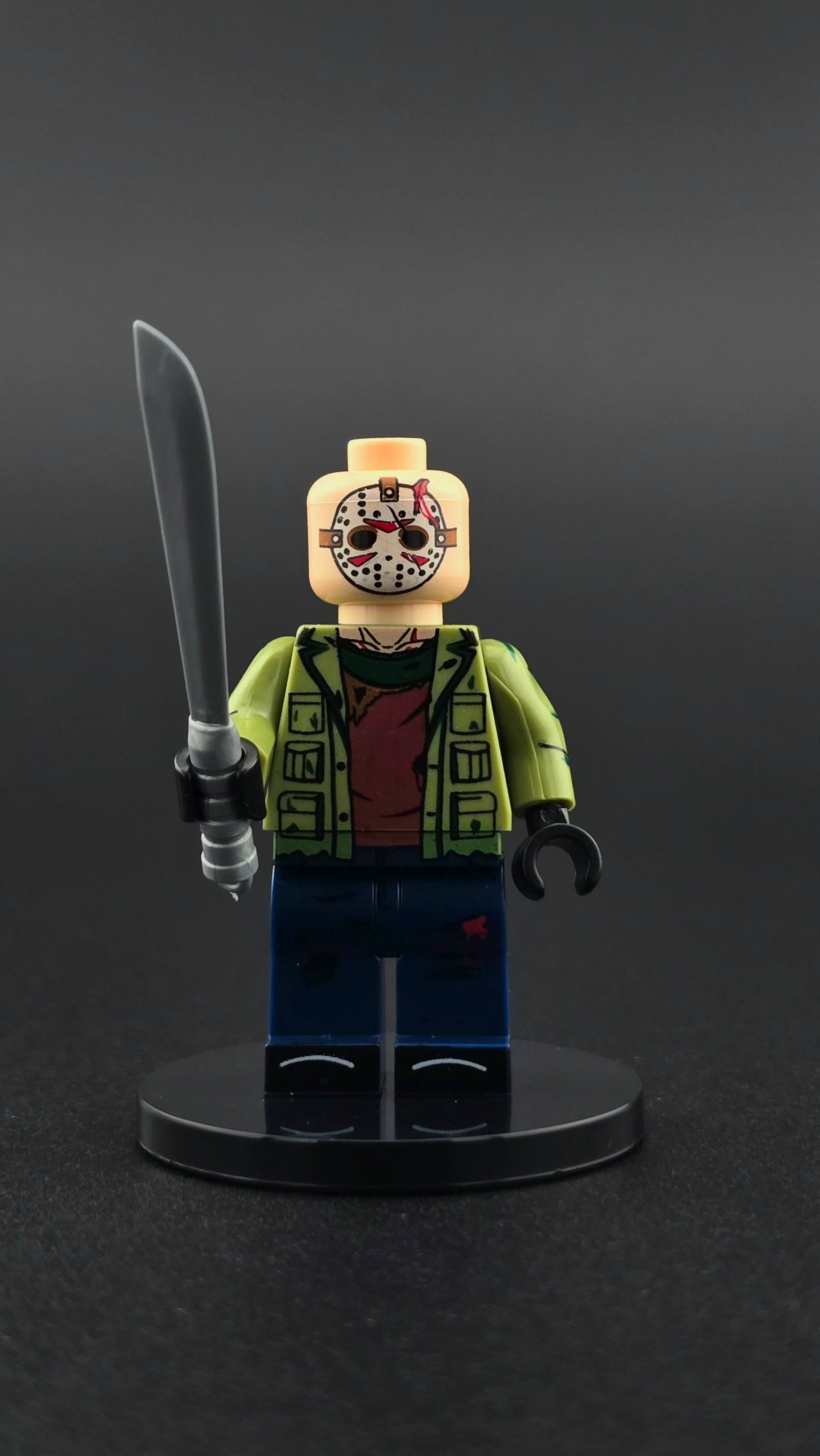 Custom horror inspired Jason style minifigure with green and blue outfit, iconic mask, and machete accessory. Detailed slasher themed design compatible with leading brick style building sets.