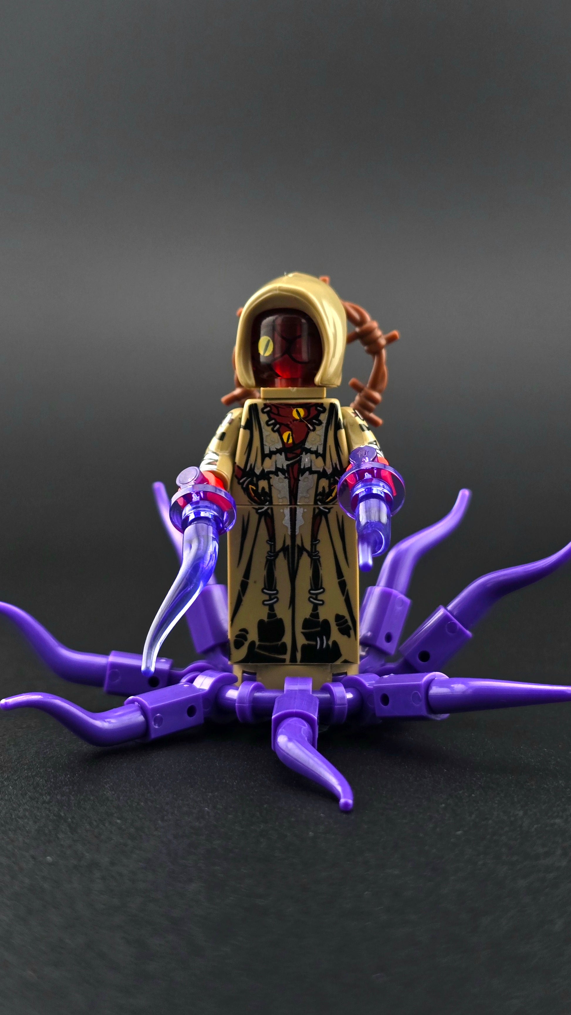 Custom Lovecraft inspired minifigure with hooded design, multiple eyes, purple and tan colours, and tentacle accessory. Eldritch themed figure with detailed horror styling compatible with leading brick style building sets.
