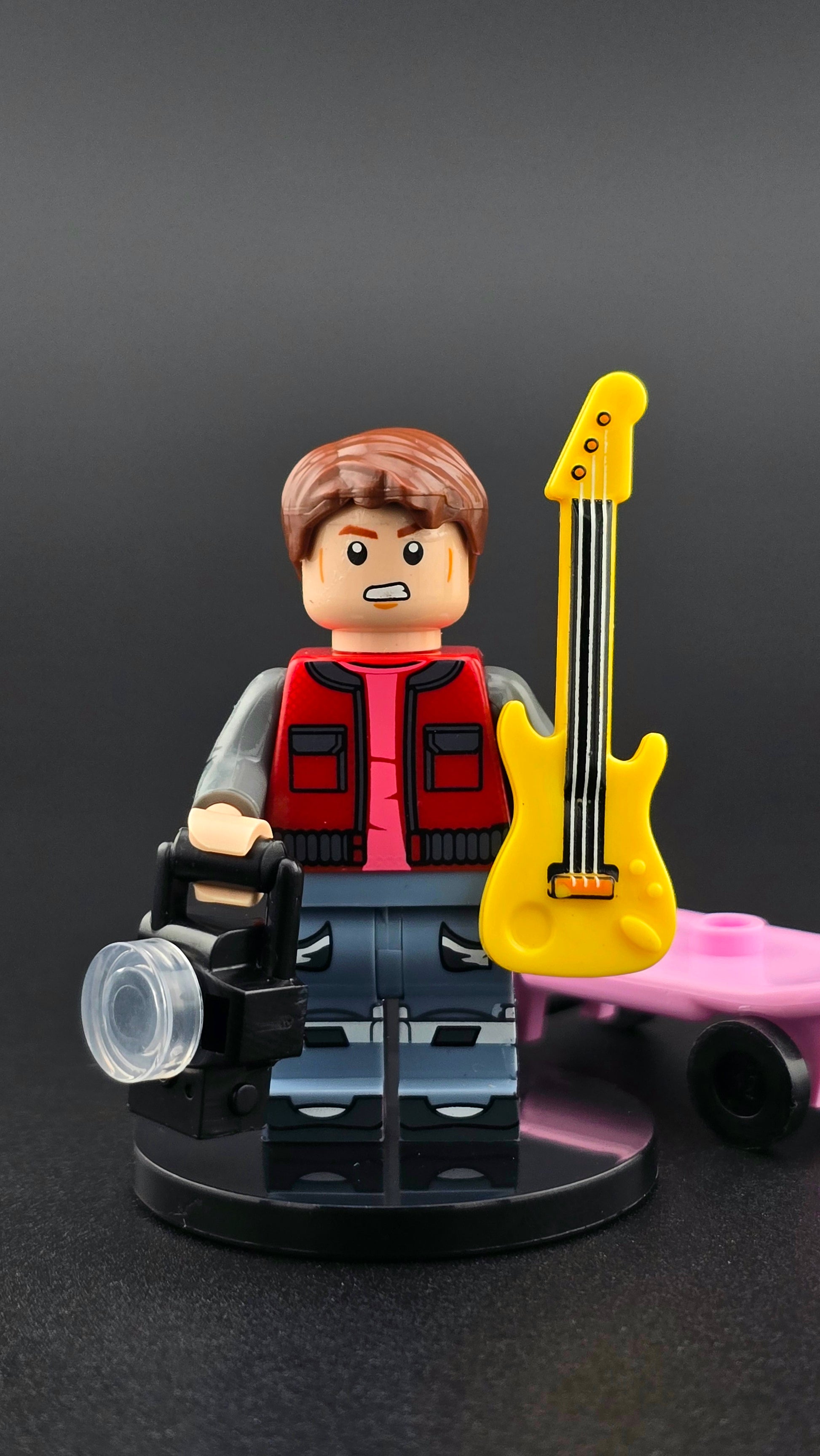 Custom movie-inspired Marty McFly minifigure in layered 80s outfit with guitar, camera, and skateboard accessories, styled in black tones and compatible with leading brick-style building systems.
